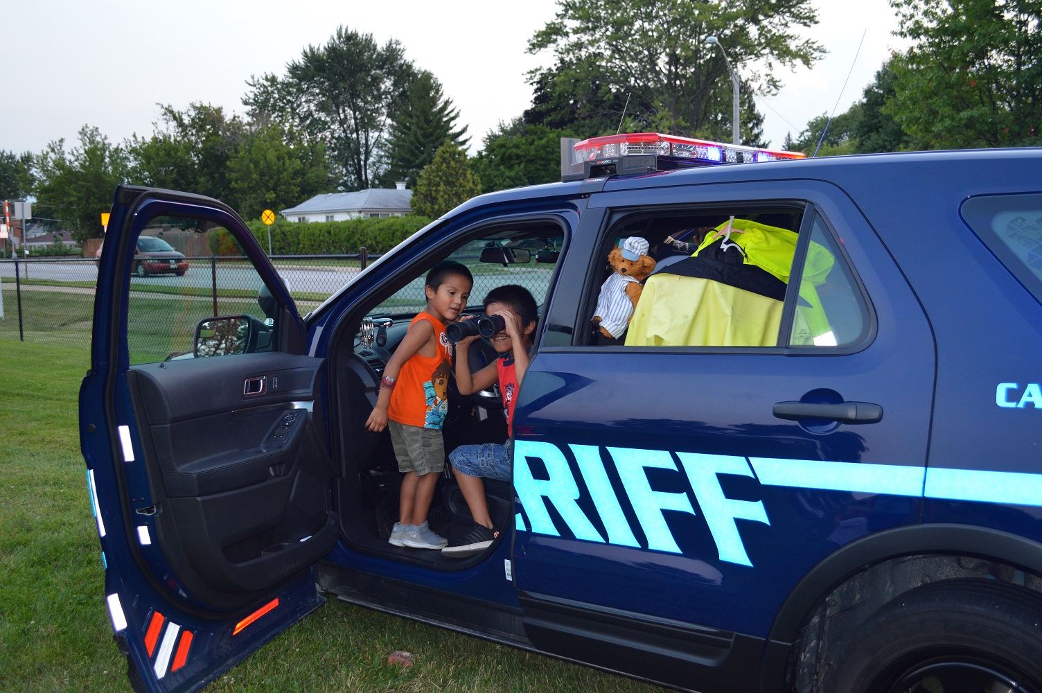 Children take turns looking through binoculars from a DuPage County Sheriff's vehicle during a National Night Out event at the Iowa Community Center, Aug. 2.